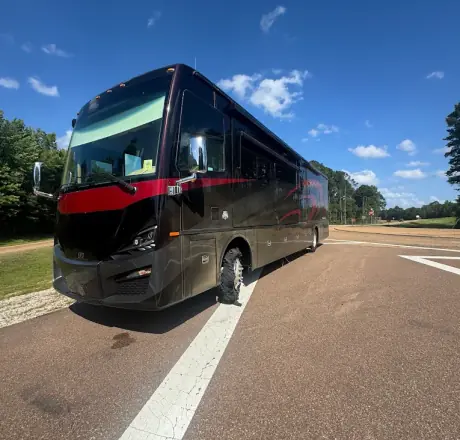 Class A motorhome pulled over on the roadside with a completely shredded tire on the front axle