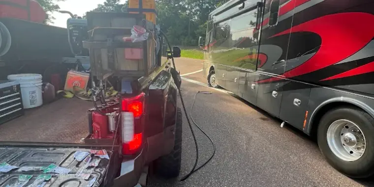Breaux's Roadside service truck with tools and tire supplies laid out, parked alongside a Class A motorhome for on-site tire service