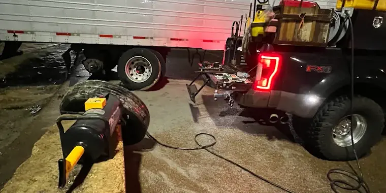 Night-time roadside tire service on a semi trailer, lit by the Breaux's Roadside service truck